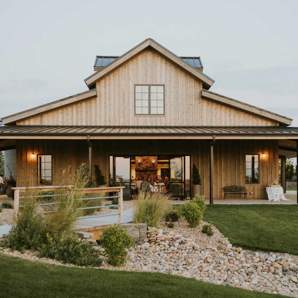A beautiful contemporary modern home with farm influences is offset perfectly by a well-kept lawn with decorative landscaping.